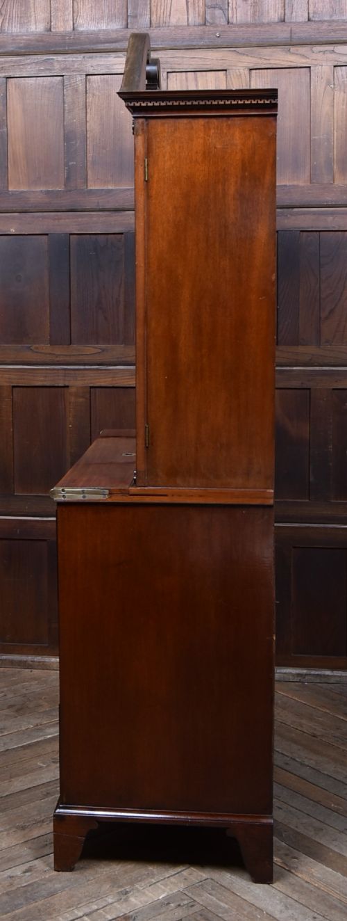An early nineteenth-century mahogany secretaire bookcase featuring a swan-neck pediment, astragal glazed upper doors, and a lower chest of drawers with brass lion-head handles. View XII