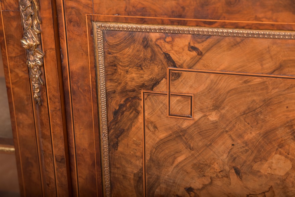 A Victorian burr walnut credenza featuring a central inlaid cupboard door flanked by curved glass display sections with gilt-bronze mounts. View VII