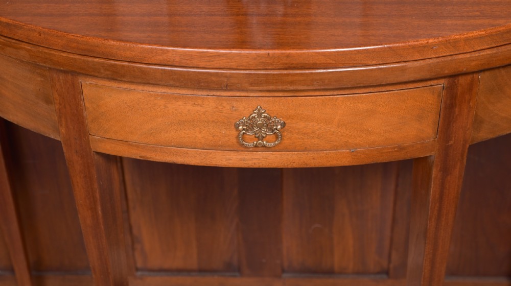 An Edwardian mahogany demi-lune fold-over tea table supported by four tapered square legs with a single frieze drawer. View III