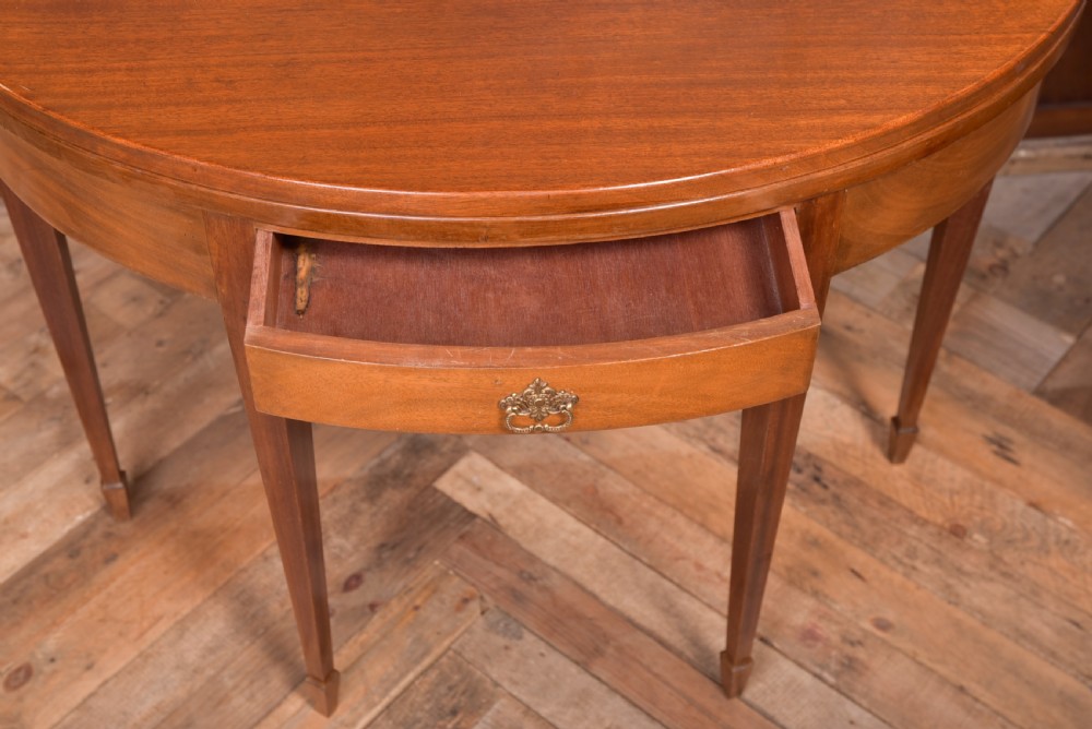An Edwardian mahogany demi-lune fold-over tea table supported by four tapered square legs with a single frieze drawer. View XII