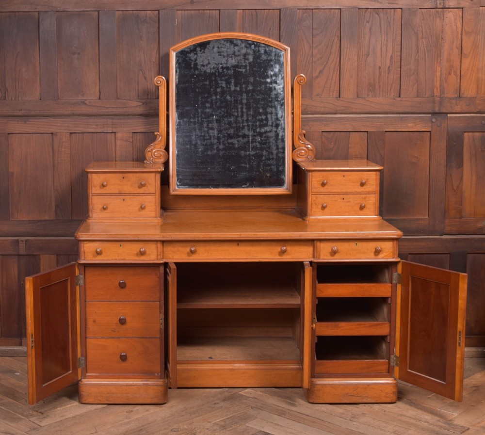 A Victorian satinwood dressing table featuring an arched central swivel mirror, trinket drawers, frieze drawers, and lower pedestal cupboards. View II