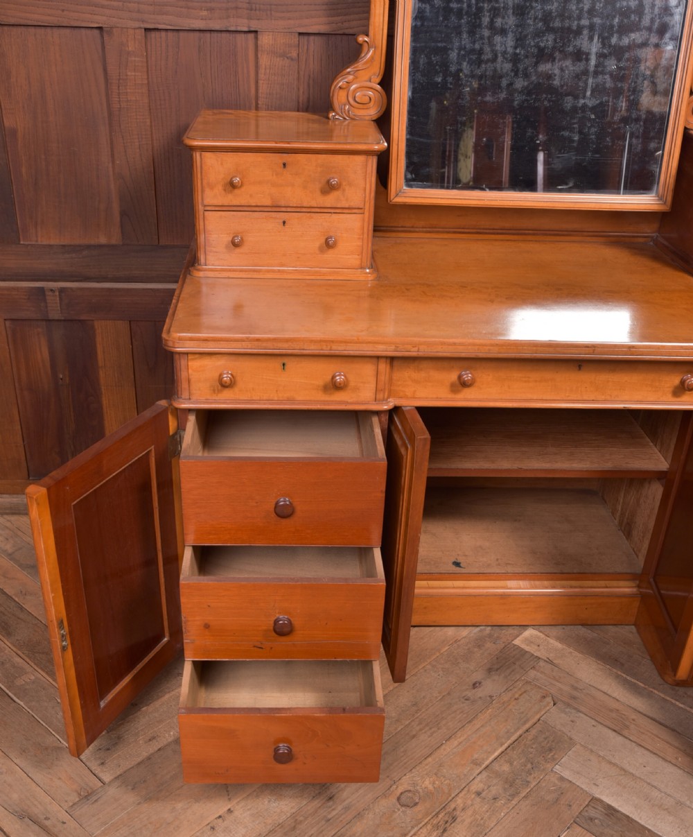 A Victorian satinwood dressing table featuring an arched central swivel mirror, trinket drawers, frieze drawers, and lower pedestal cupboards. View III