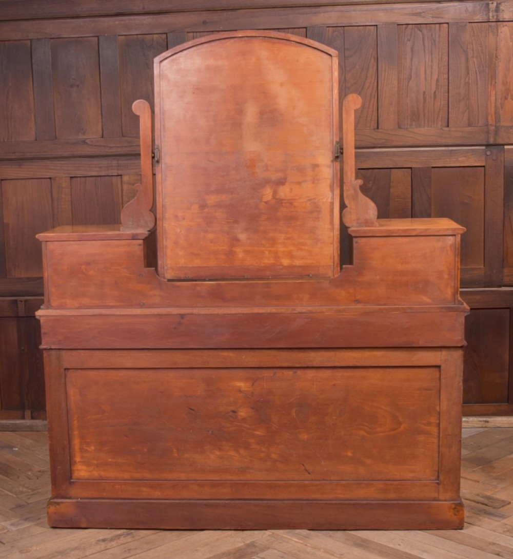 A Victorian satinwood dressing table featuring an arched central swivel mirror, trinket drawers, frieze drawers, and lower pedestal cupboards. View XI