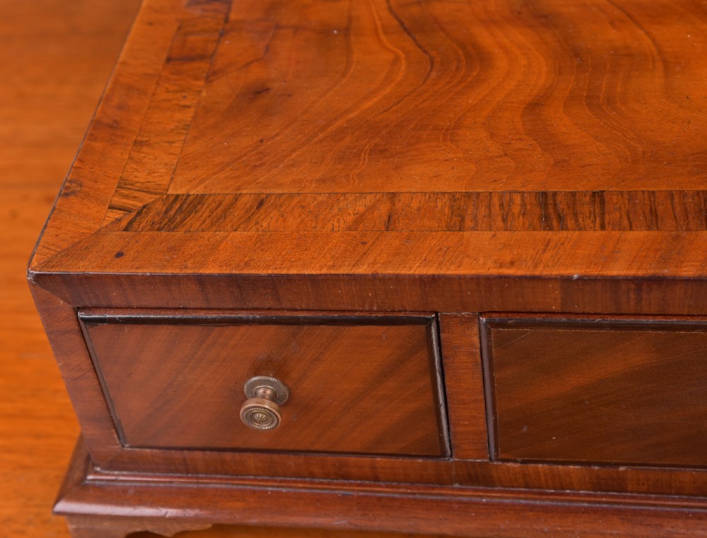An antique mahogany oval toilet mirror with curved horn supports atop a plinth base containing three small drawers. View X