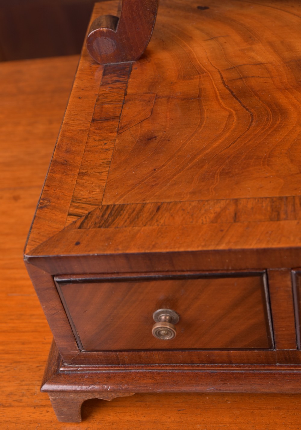 An antique mahogany oval toilet mirror with curved horn supports atop a plinth base containing three small drawers. View XI