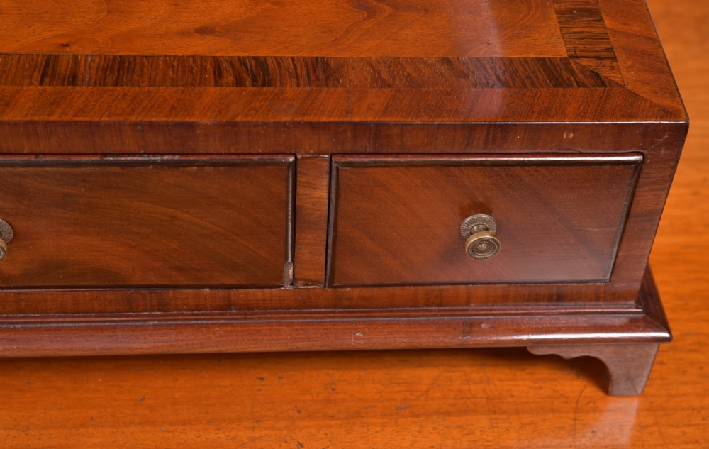 An antique mahogany oval toilet mirror with curved horn supports atop a plinth base containing three small drawers. View XIII
