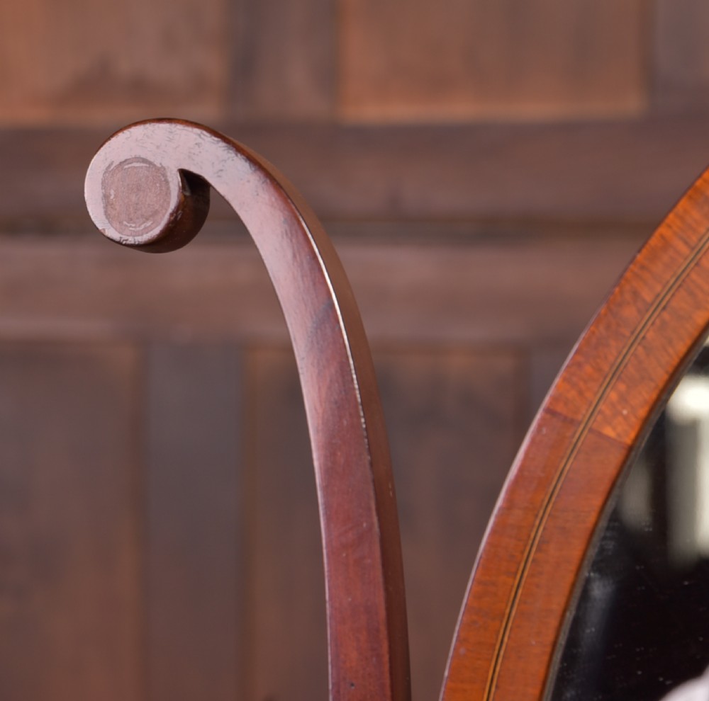 An antique mahogany oval toilet mirror with curved horn supports atop a plinth base containing three small drawers. View XVI