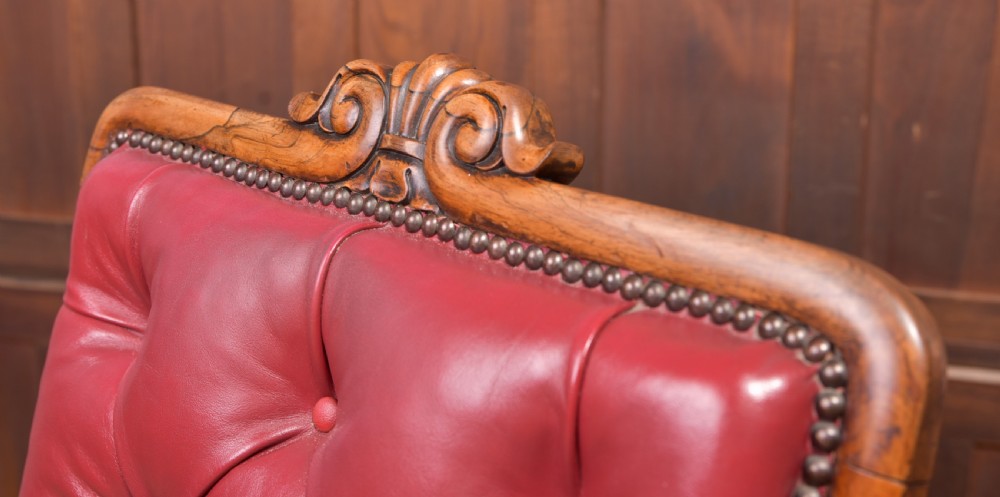 A Regency period rosewood armchair featuring dark red button-tufted leather upholstery, scrolled armrests, brass castors, and carved timber detailing. View II