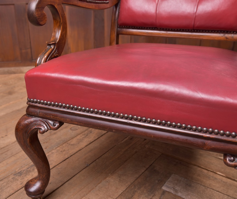 A Regency period rosewood armchair featuring dark red button-tufted leather upholstery, scrolled armrests, brass castors, and carved timber detailing. View VIII