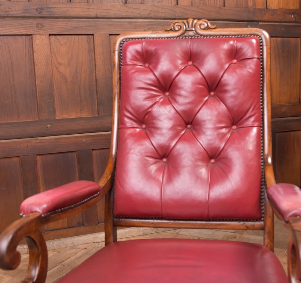 A Regency period rosewood armchair featuring dark red button-tufted leather upholstery, scrolled armrests, brass castors, and carved timber detailing. View XI