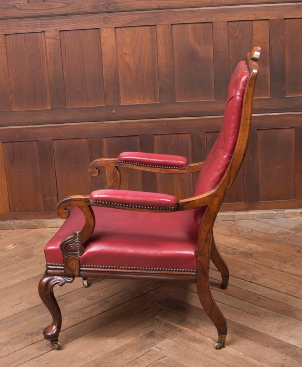 A Regency period rosewood armchair featuring dark red button-tufted leather upholstery, scrolled armrests, brass castors, and carved timber detailing. View XII