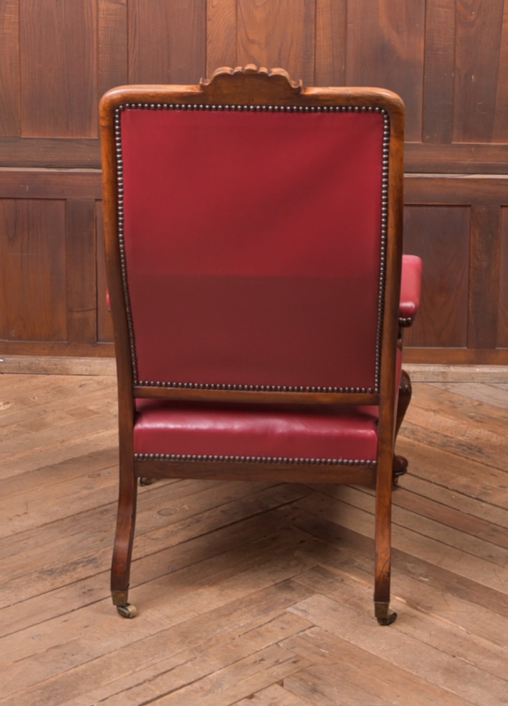 A Regency period rosewood armchair featuring dark red button-tufted leather upholstery, scrolled armrests, brass castors, and carved timber detailing. View XIII