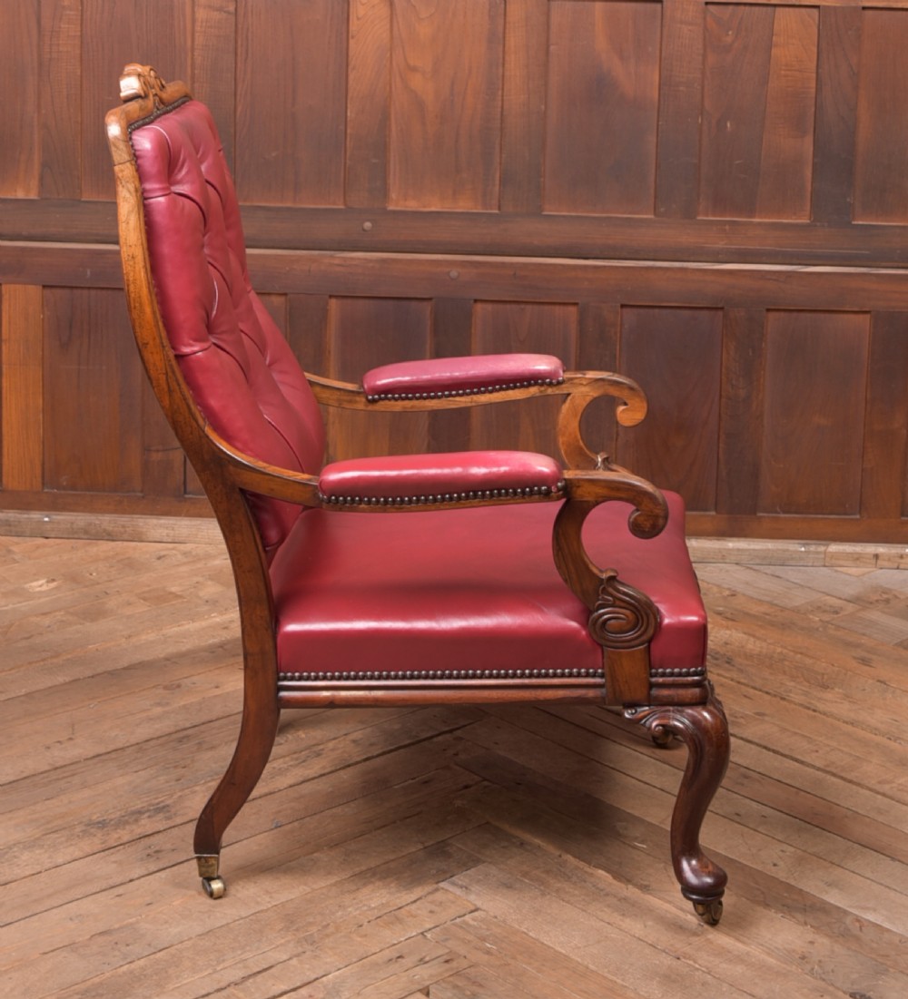 A Regency period rosewood armchair featuring dark red button-tufted leather upholstery, scrolled armrests, brass castors, and carved timber detailing. View XVII