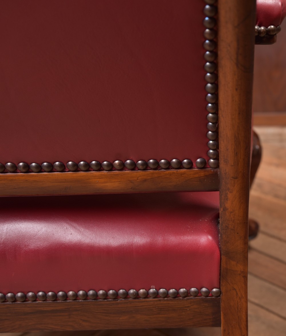 A Regency period rosewood armchair featuring dark red button-tufted leather upholstery, scrolled armrests, brass castors, and carved timber detailing. View XIX