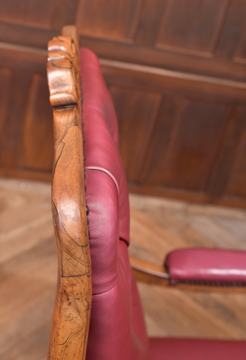 A Regency period rosewood armchair featuring dark red button-tufted leather upholstery, scrolled armrests, brass castors, and carved timber detailing. View XX