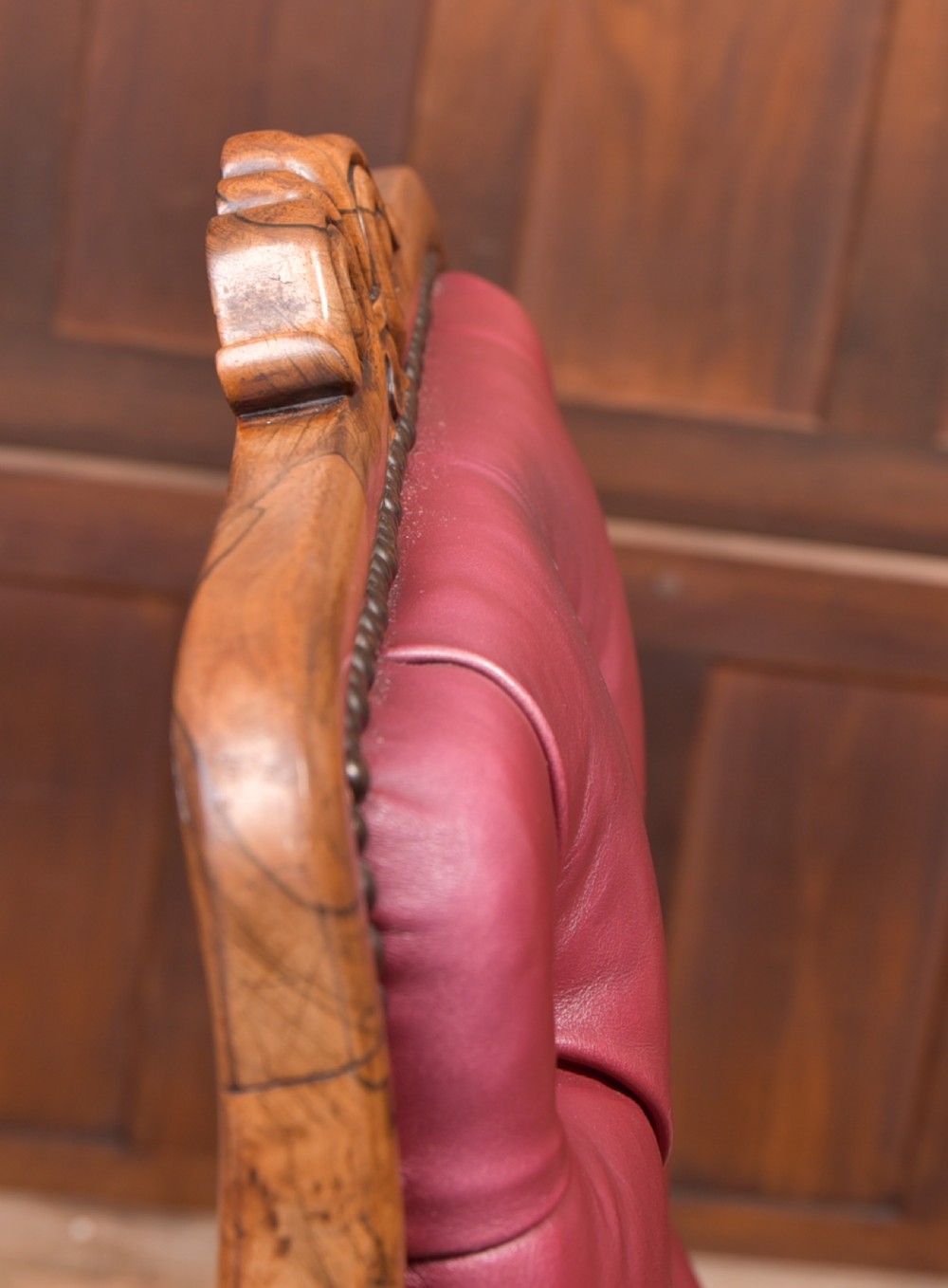 A Regency period rosewood armchair featuring dark red button-tufted leather upholstery, scrolled armrests, brass castors, and carved timber detailing. View XXI