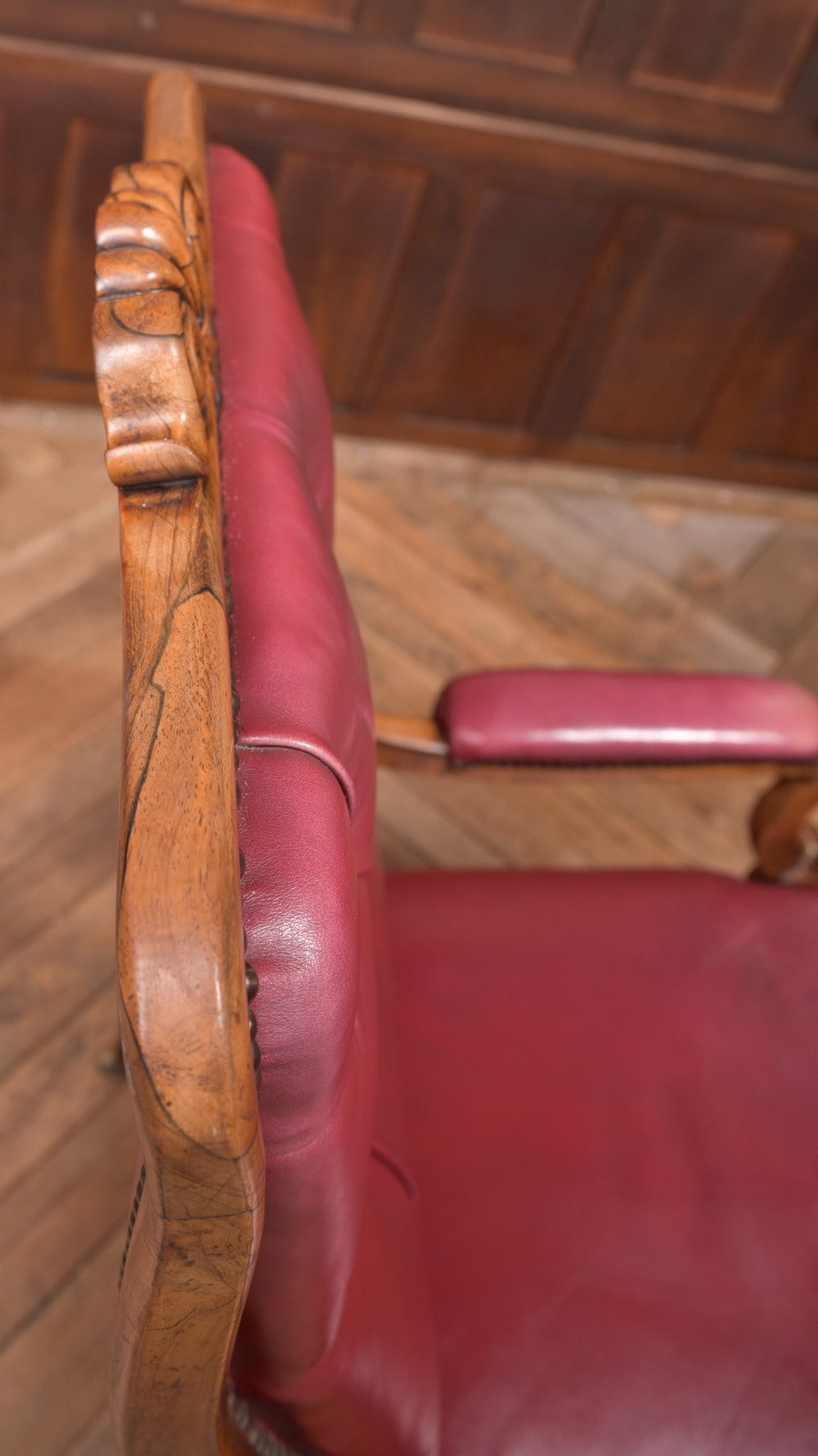A Regency period rosewood armchair featuring dark red button-tufted leather upholstery, scrolled armrests, brass castors, and carved timber detailing. View XXII