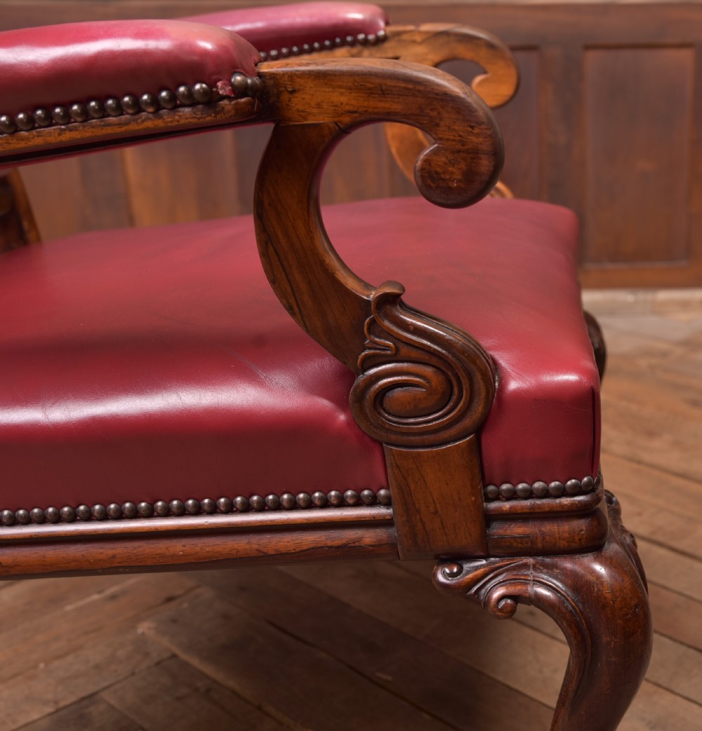 A Regency period rosewood armchair featuring dark red button-tufted leather upholstery, scrolled armrests, brass castors, and carved timber detailing. View XXIII