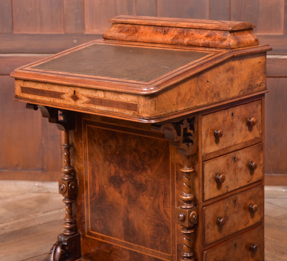 A Victorian burr walnut Davenport desk featuring a slanted leather writing surface, decorative carved supports, and a side bank of drawers. View II