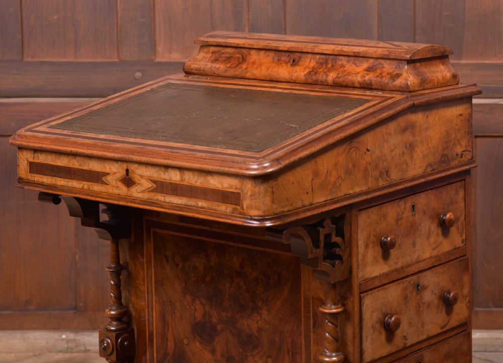 A Victorian burr walnut Davenport desk featuring a slanted leather writing surface, decorative carved supports, and a side bank of drawers. View III
