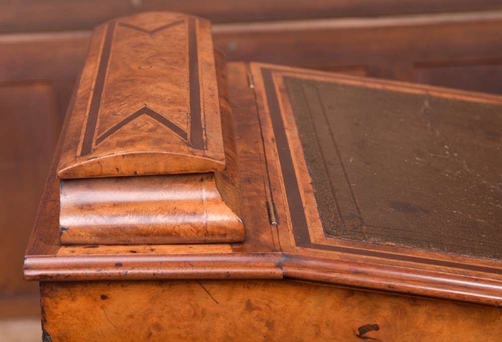 A Victorian burr walnut Davenport desk featuring a slanted leather writing surface, decorative carved supports, and a side bank of drawers. View XI