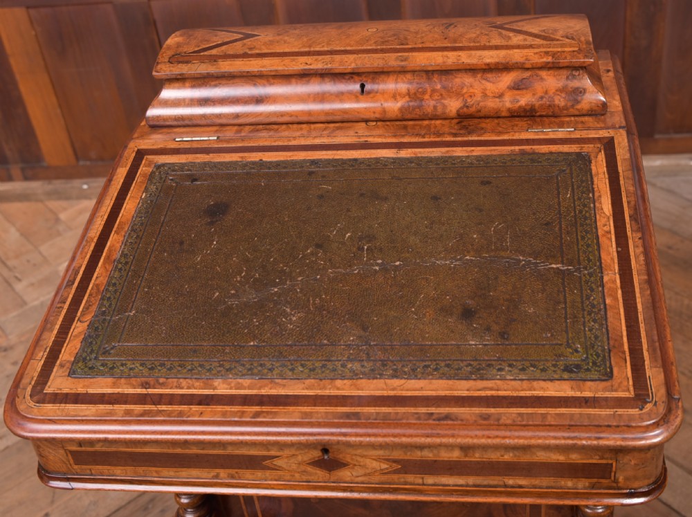 A Victorian burr walnut Davenport desk featuring a slanted leather writing surface, decorative carved supports, and a side bank of drawers. View XII