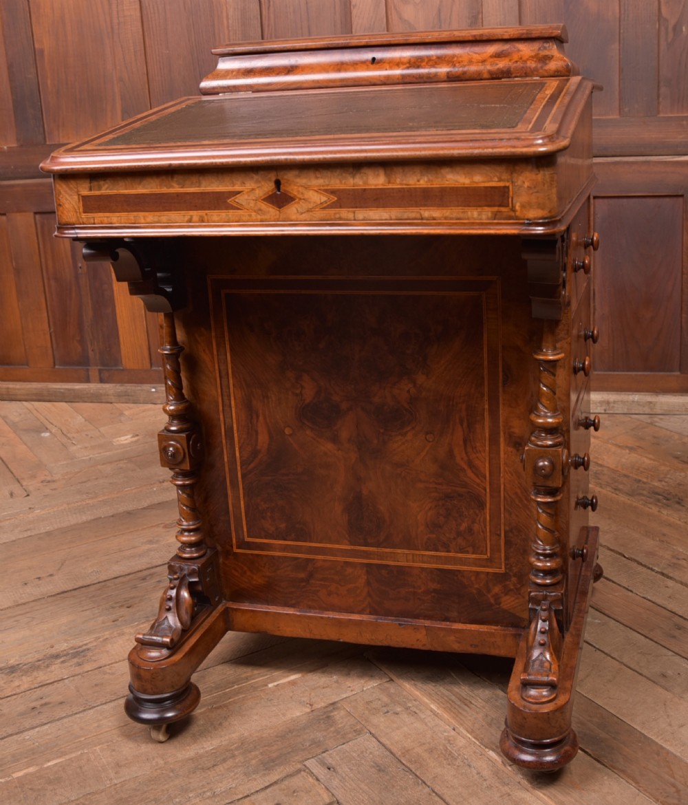 A Victorian burr walnut Davenport desk featuring a slanted leather writing surface, decorative carved supports, and a side bank of drawers. View XIV