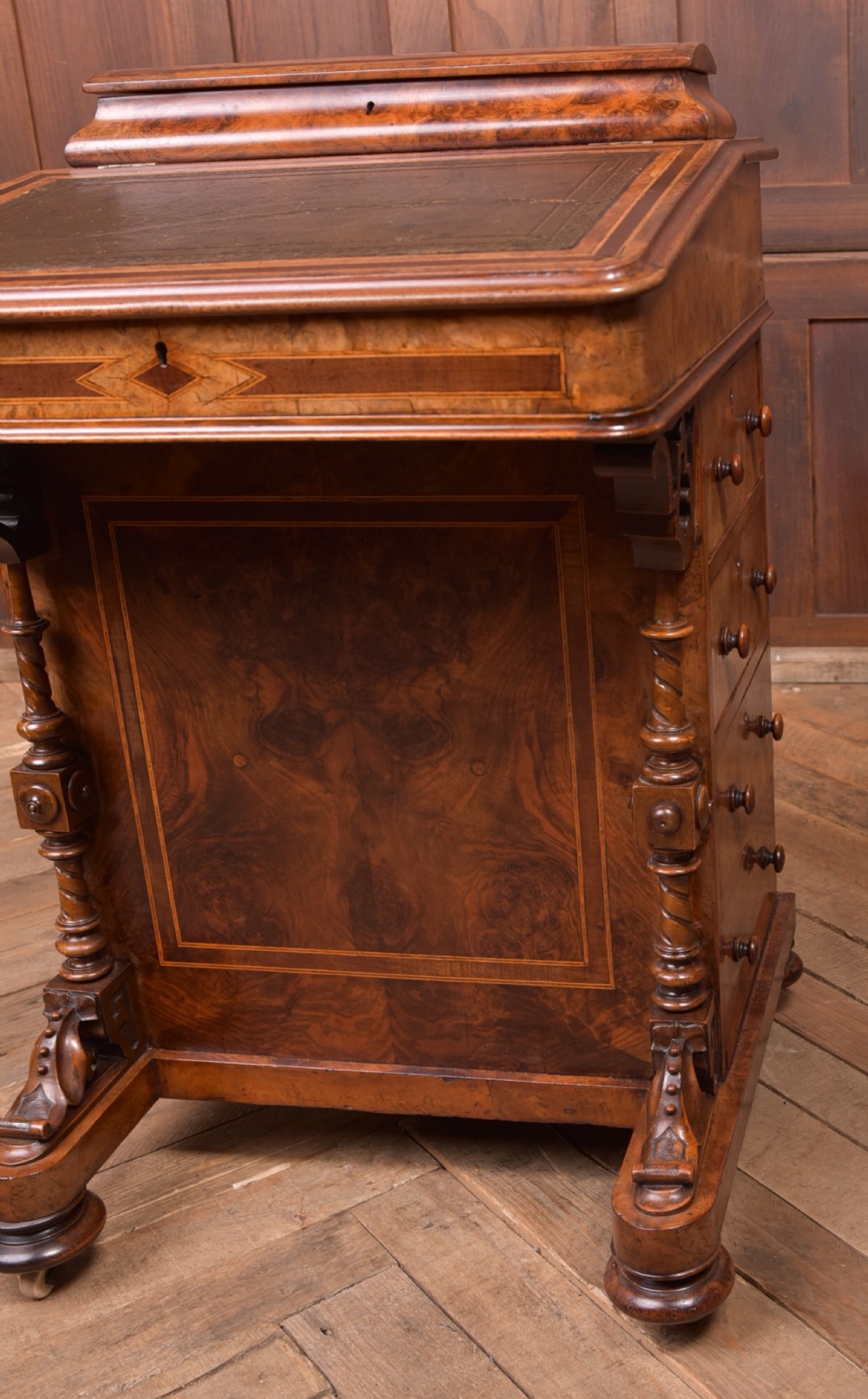 A Victorian burr walnut Davenport desk featuring a slanted leather writing surface, decorative carved supports, and a side bank of drawers. View XVI