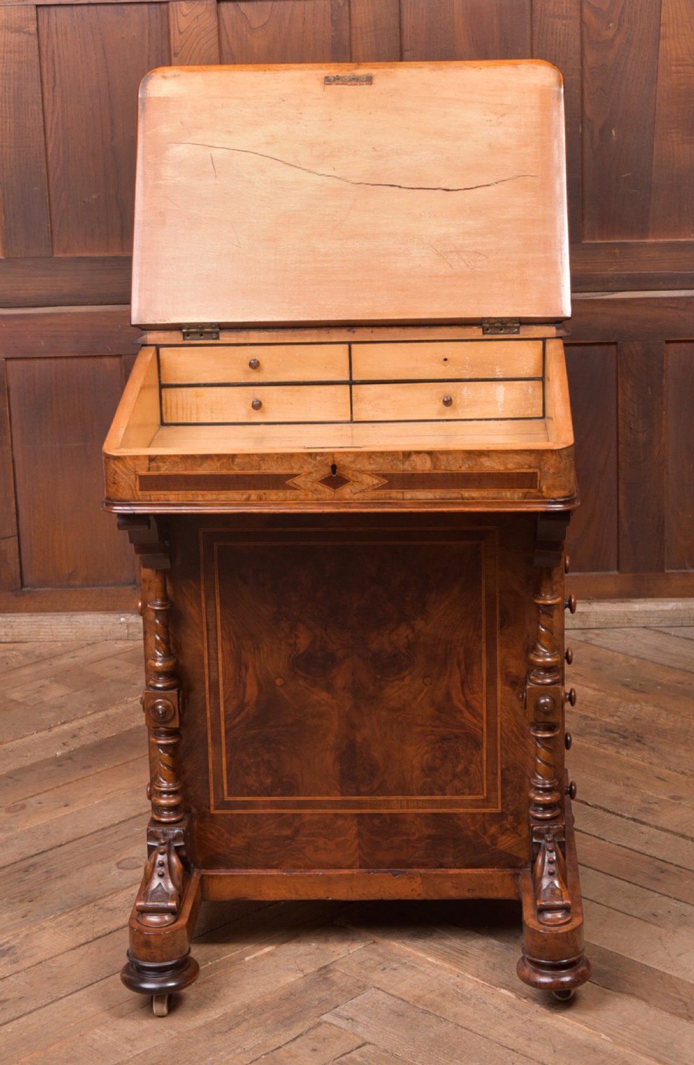 A Victorian burr walnut Davenport desk featuring a slanted leather writing surface, decorative carved supports, and a side bank of drawers. View XVIII