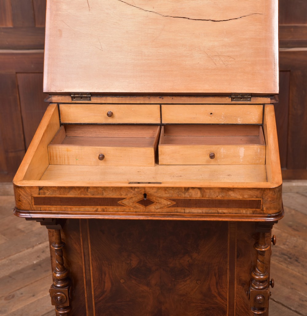 A Victorian burr walnut Davenport desk featuring a slanted leather writing surface, decorative carved supports, and a side bank of drawers. View XX