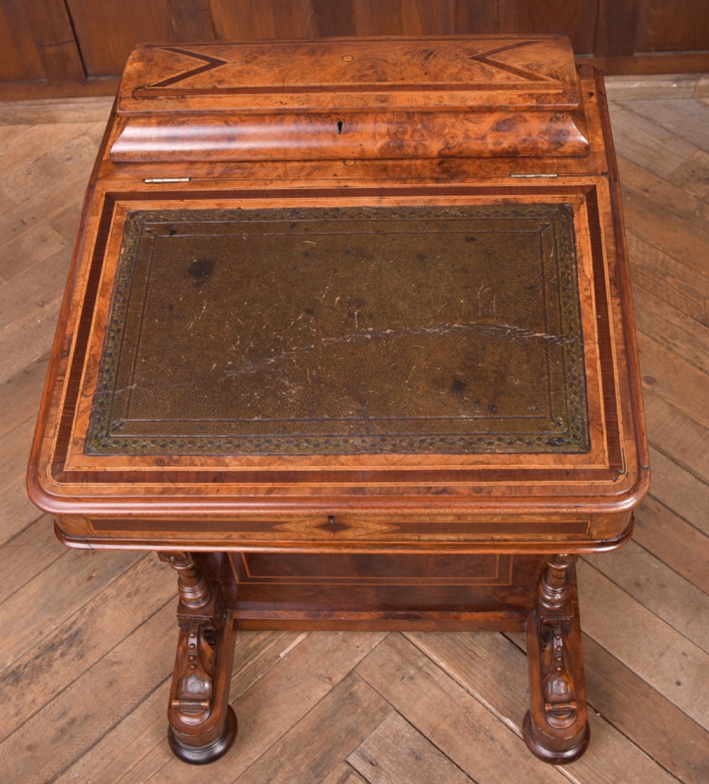 A Victorian burr walnut Davenport desk featuring a slanted leather writing surface, decorative carved supports, and a side bank of drawers. View XXII
