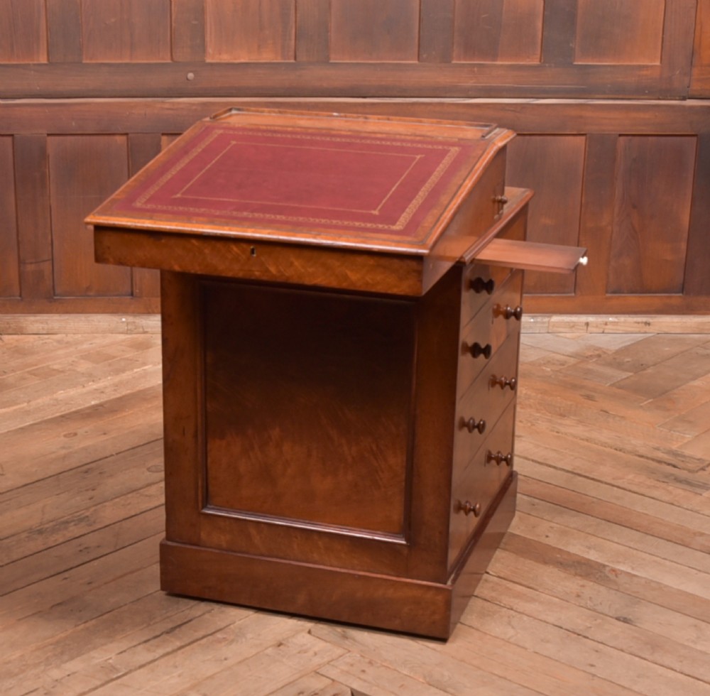A Victorian walnut Davenport desk featuring a slanted burgundy leather writing surface, side drawers with wooden knobs, and a solid rectangular base. View IV