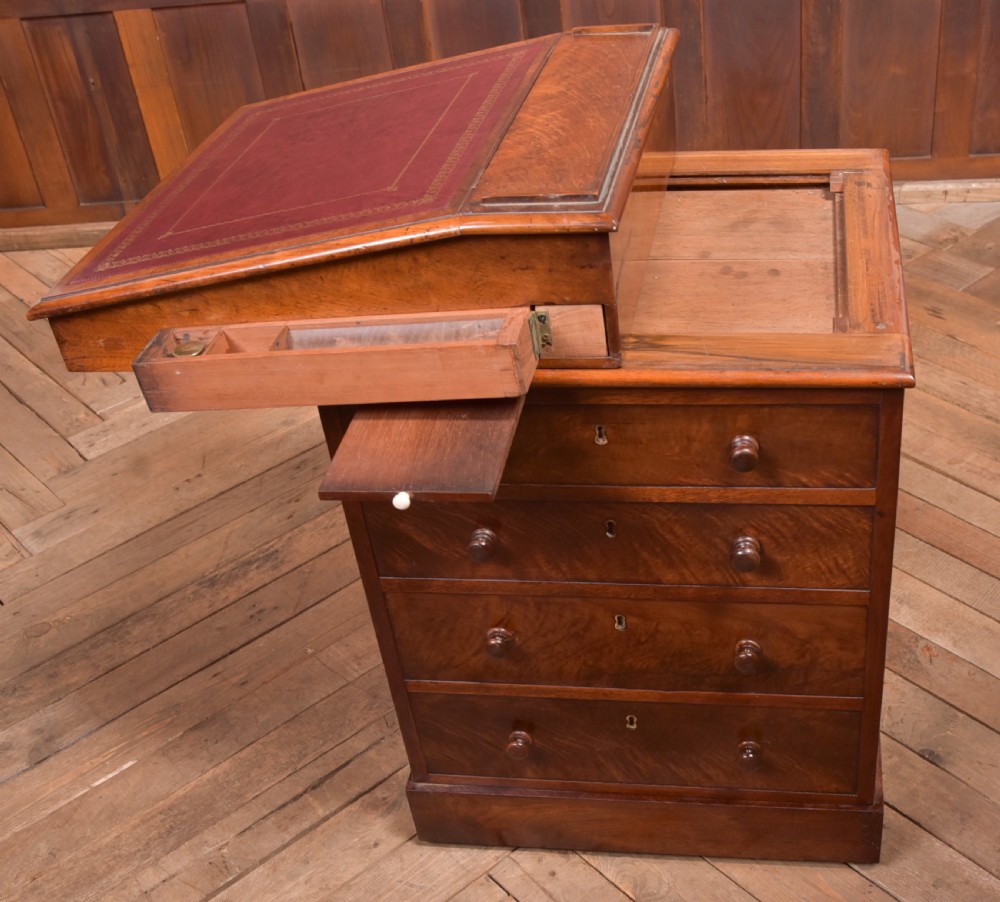 A Victorian walnut Davenport desk featuring a slanted burgundy leather writing surface, side drawers with wooden knobs, and a solid rectangular base. View VIII