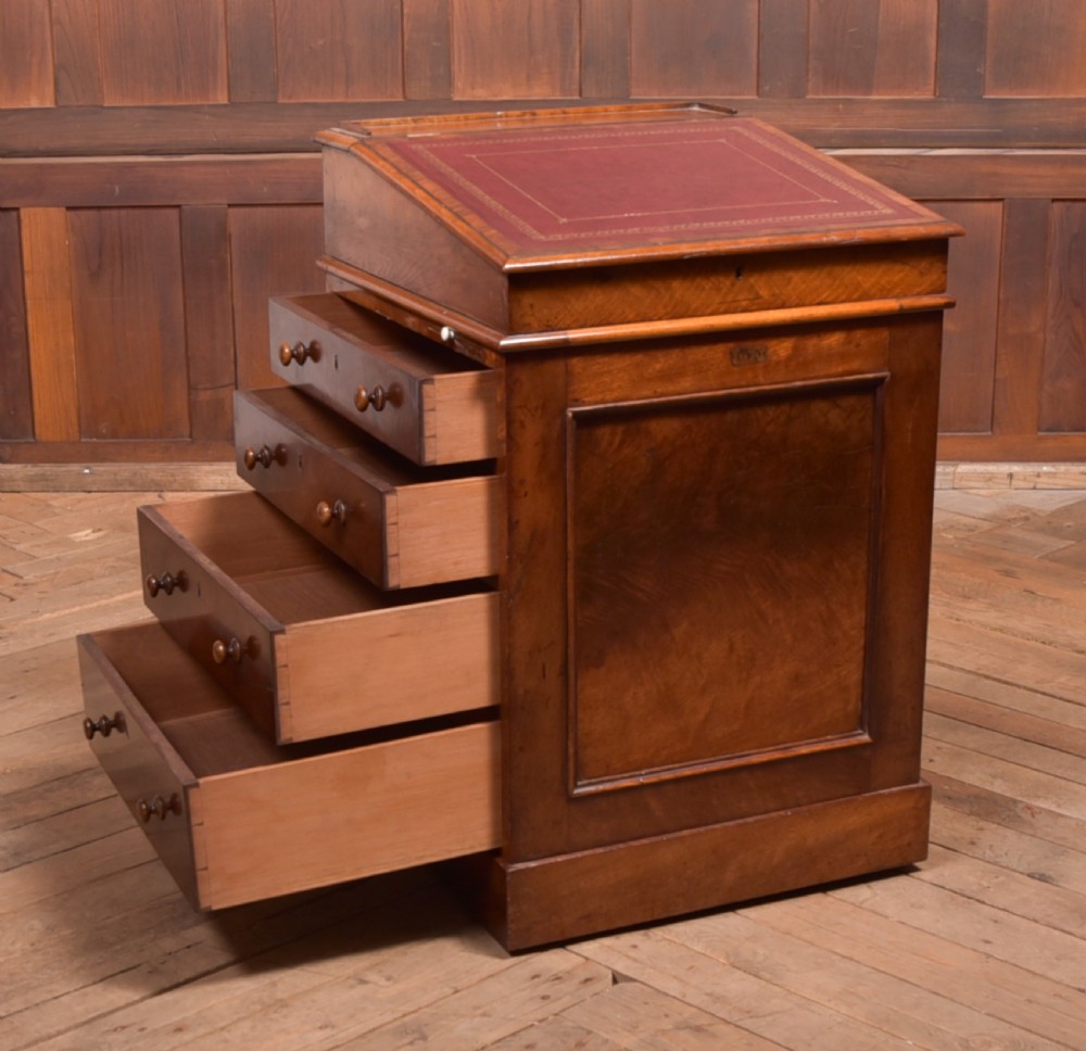 A Victorian walnut Davenport desk featuring a slanted burgundy leather writing surface, side drawers with wooden knobs, and a solid rectangular base. View X