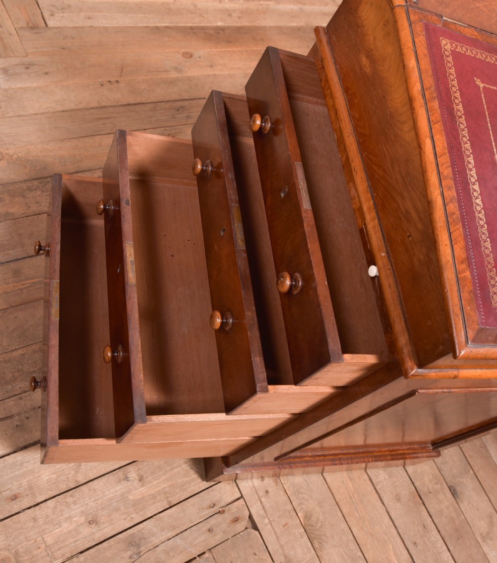 A Victorian walnut Davenport desk featuring a slanted burgundy leather writing surface, side drawers with wooden knobs, and a solid rectangular base. View XI