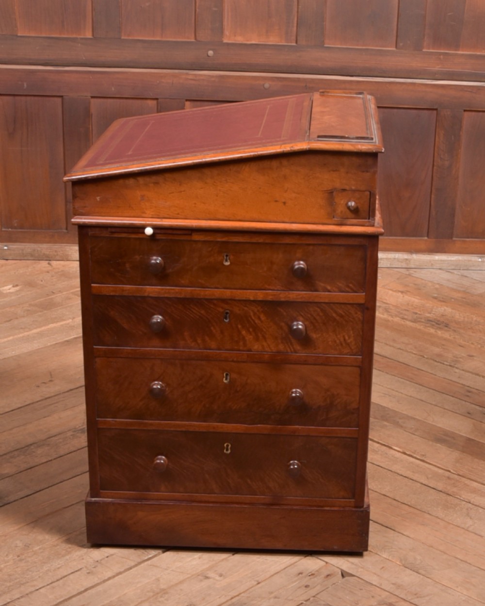 A Victorian walnut Davenport desk featuring a slanted burgundy leather writing surface, side drawers with wooden knobs, and a solid rectangular base. View XIV