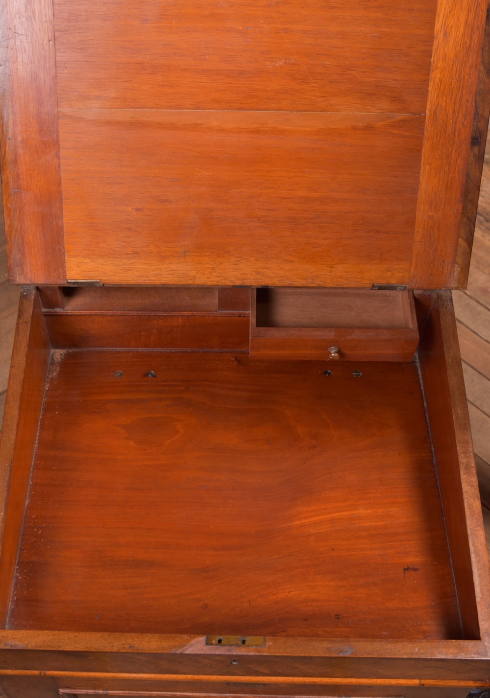 A Victorian walnut Davenport desk featuring a slanted burgundy leather writing surface, side drawers with wooden knobs, and a solid rectangular base. View XVI