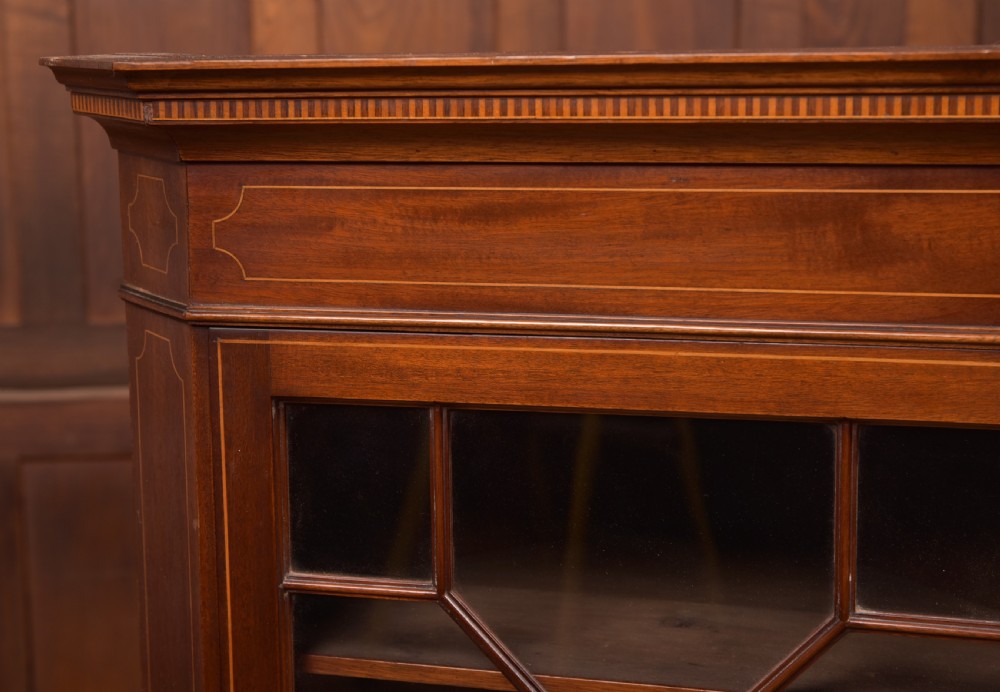 An Edwardian mahogany corner cabinet featuring astragal glazed glass panels, geometric boxwood line inlay, and internal timber shelves. View VI