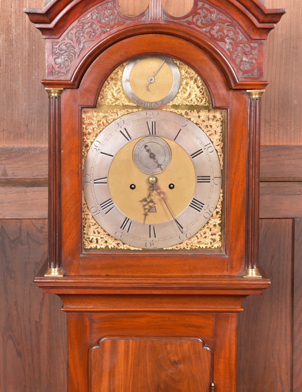 An antique Georgian flame mahogany longcase clock with a swan-neck pediment and an arched brass dial. View III