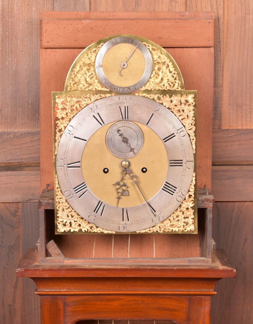 An antique Georgian flame mahogany longcase clock with a swan-neck pediment and an arched brass dial. View X