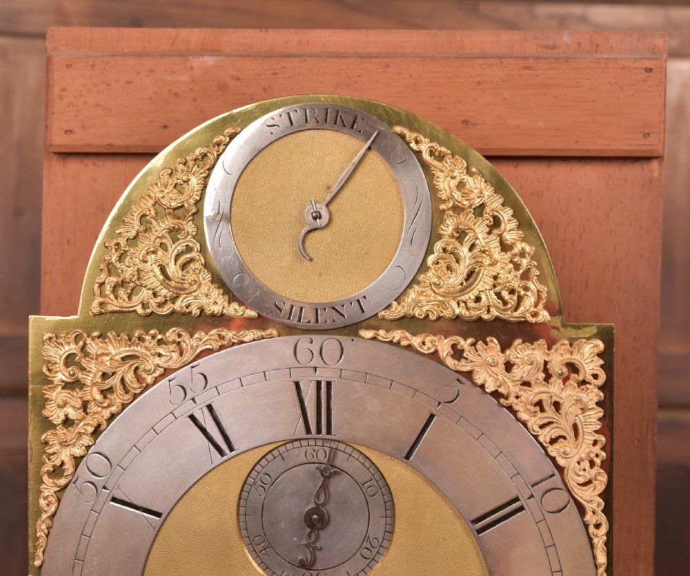 An antique Georgian flame mahogany longcase clock with a swan-neck pediment and an arched brass dial. View XIII