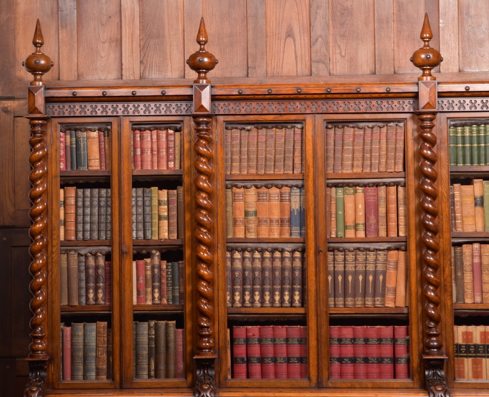 A large Victorian oak bookcase featuring glazed upper doors flanked by barley twist columns with turned finials above carved diamond panel doors. View III