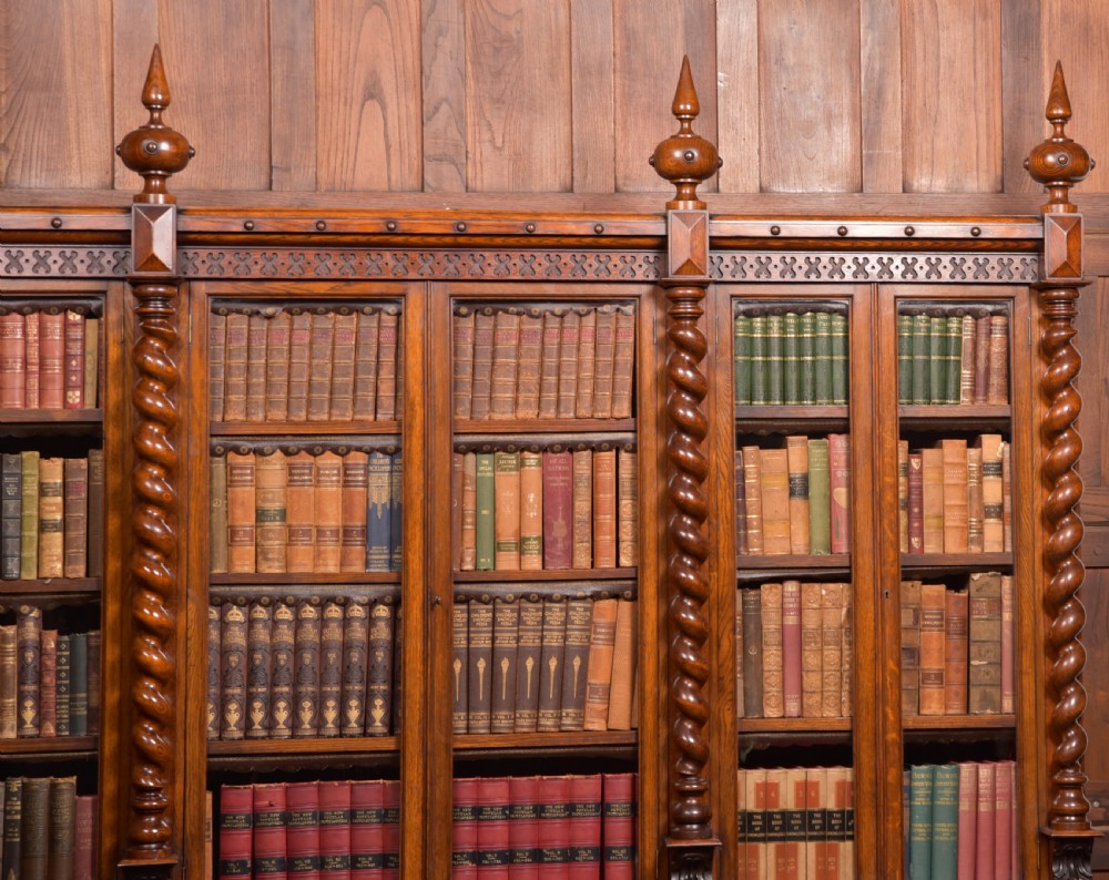 A large Victorian oak bookcase featuring glazed upper doors flanked by barley twist columns with turned finials above carved diamond panel doors. View V
