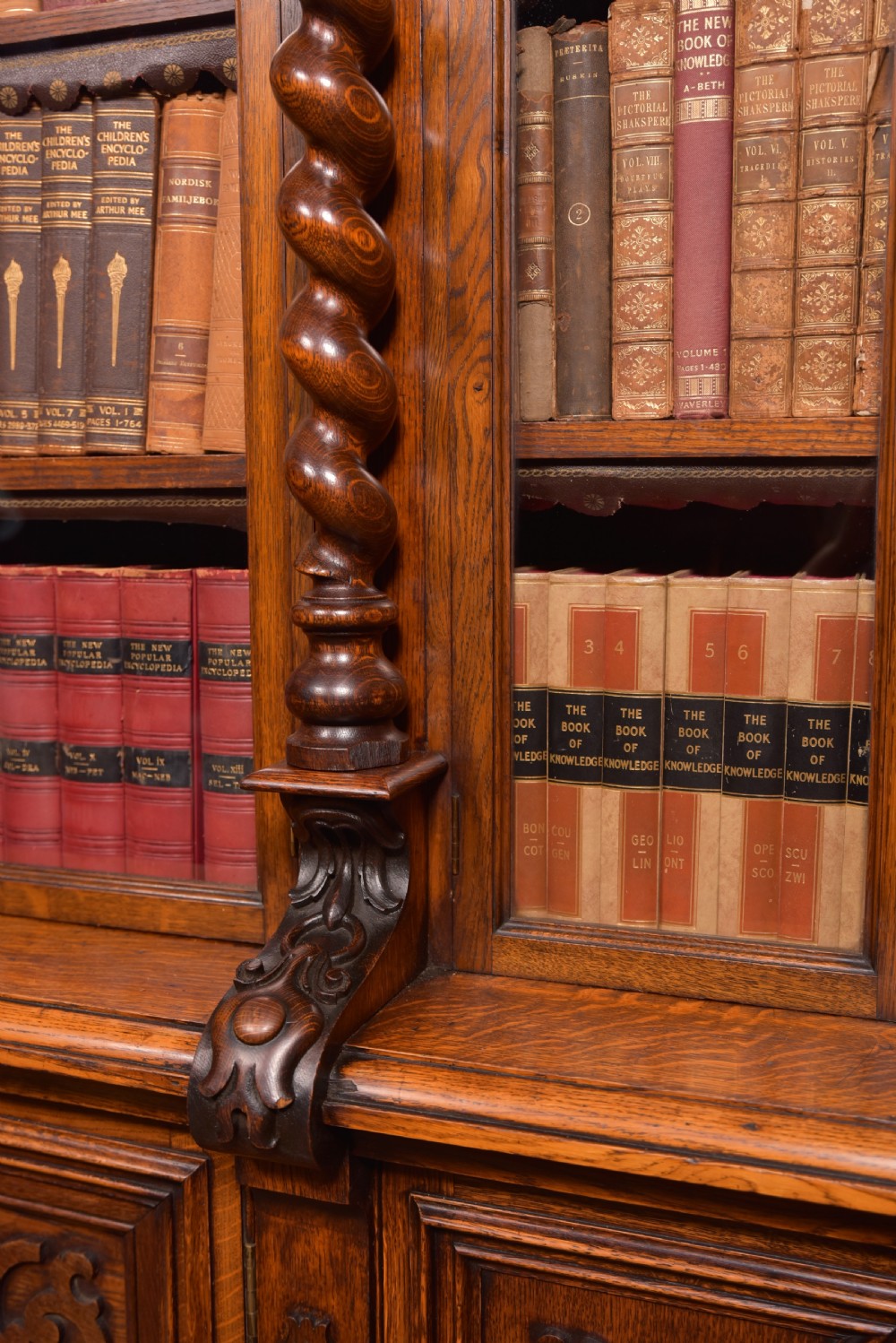 A large Victorian oak bookcase featuring glazed upper doors flanked by barley twist columns with turned finials above carved diamond panel doors. View VII