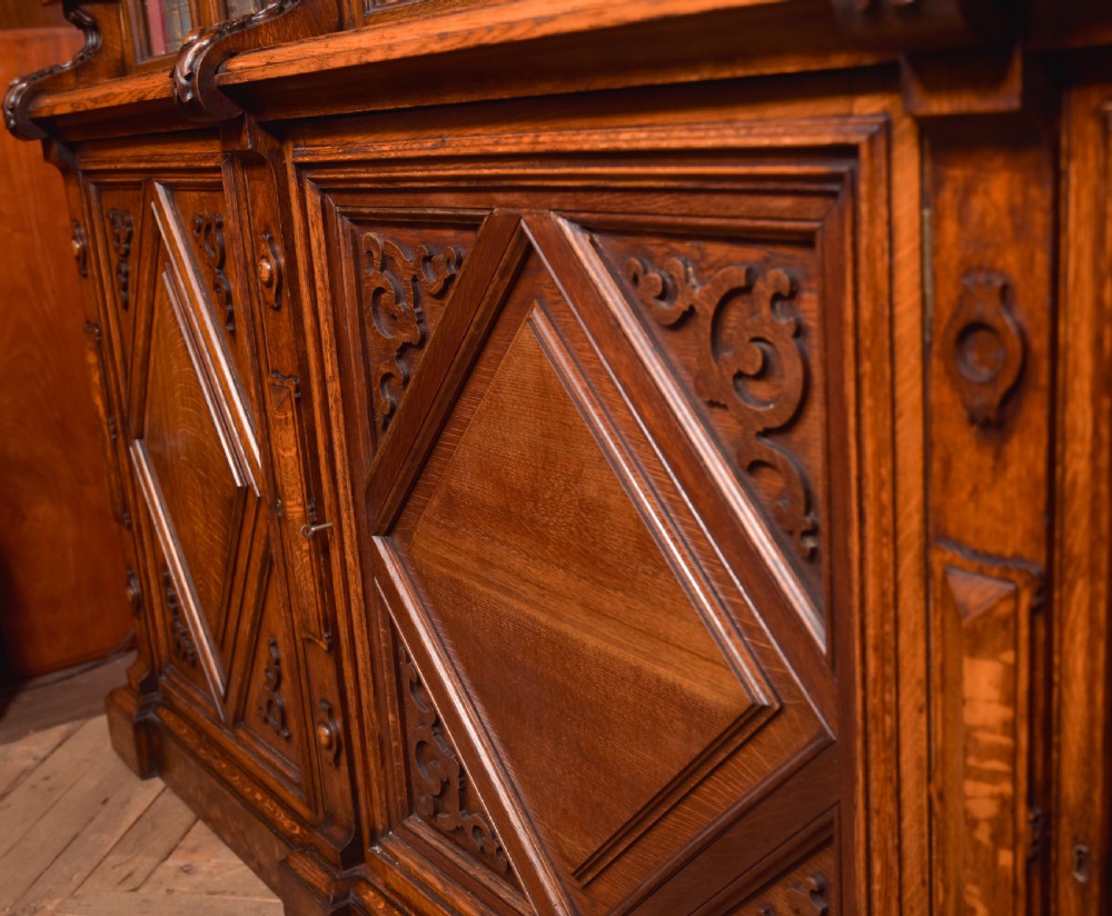 A large Victorian oak bookcase featuring glazed upper doors flanked by barley twist columns with turned finials above carved diamond panel doors. View XIII