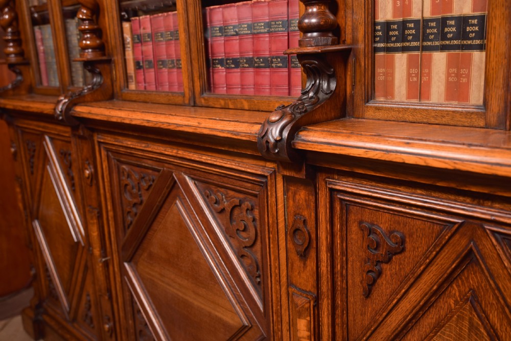 A large Victorian oak bookcase featuring glazed upper doors flanked by barley twist columns with turned finials above carved diamond panel doors. View XIV