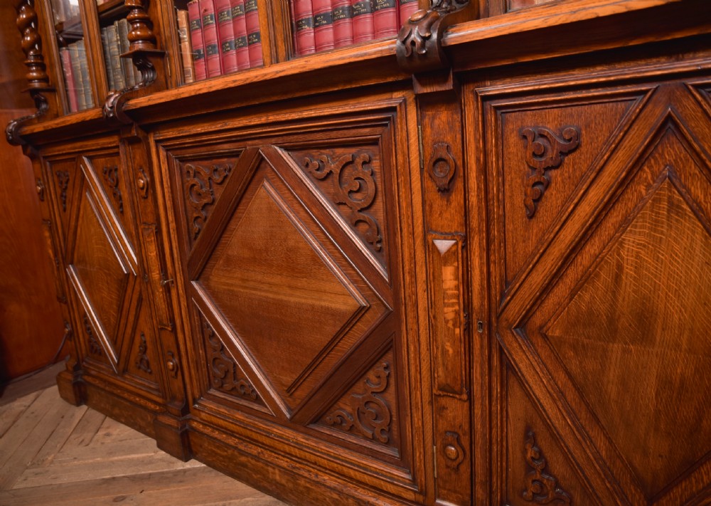 A large Victorian oak bookcase featuring glazed upper doors flanked by barley twist columns with turned finials above carved diamond panel doors. View XVIII