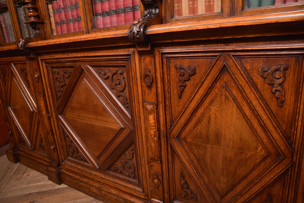 A large Victorian oak bookcase featuring glazed upper doors flanked by barley twist columns with turned finials above carved diamond panel doors. View XIX