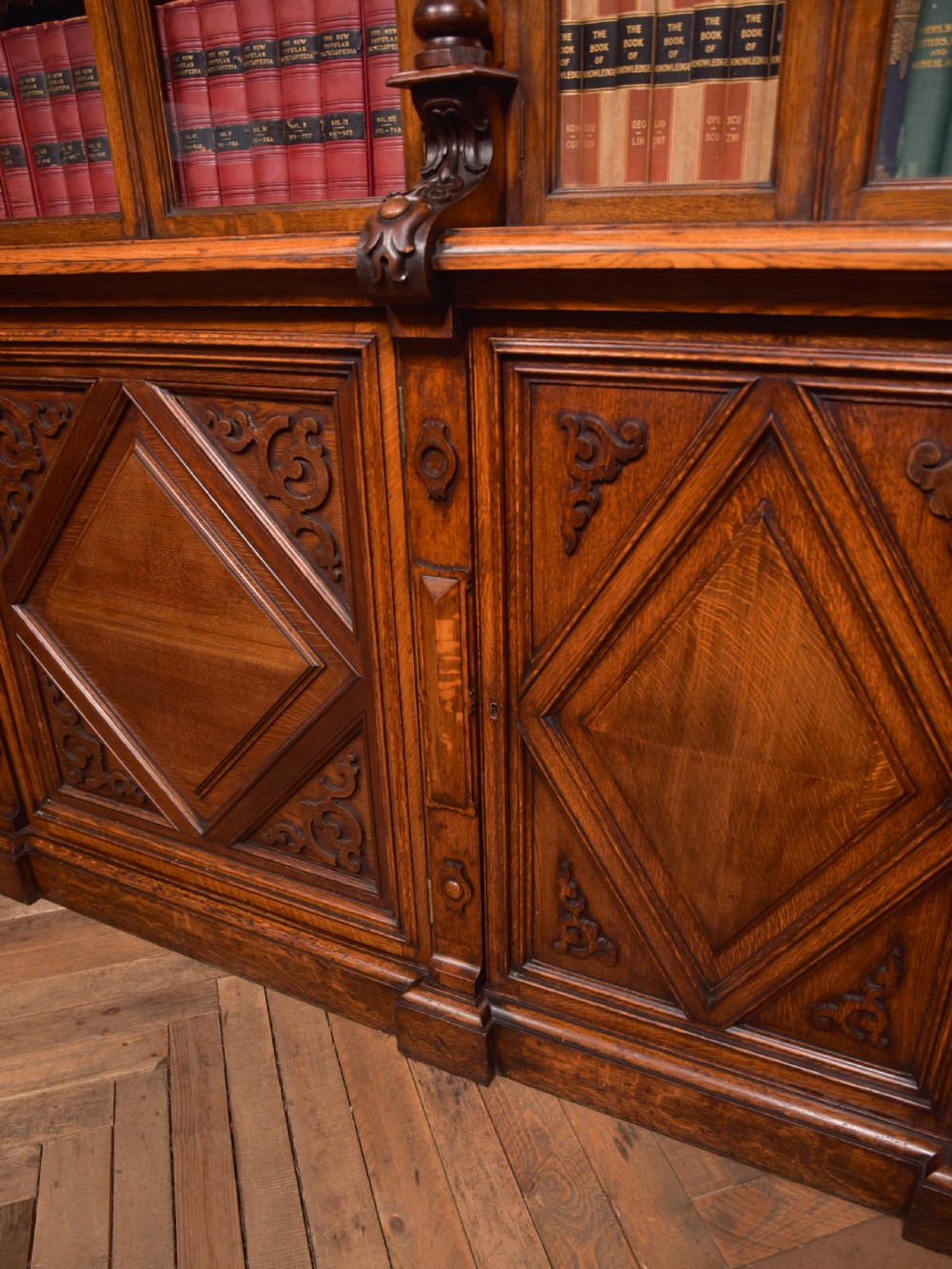 A large Victorian oak bookcase featuring glazed upper doors flanked by barley twist columns with turned finials above carved diamond panel doors. View XXI