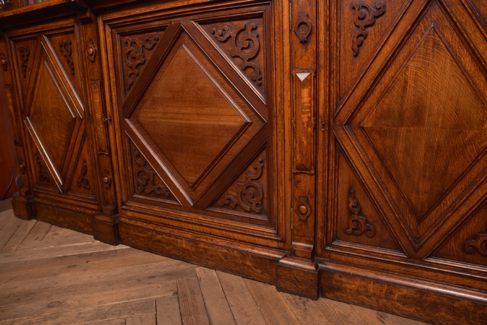 A large Victorian oak bookcase featuring glazed upper doors flanked by barley twist columns with turned finials above carved diamond panel doors. View XXII